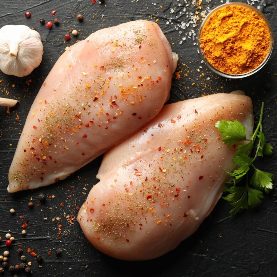 Raw chicken meat and spices on black background, top view. Cooking chicken