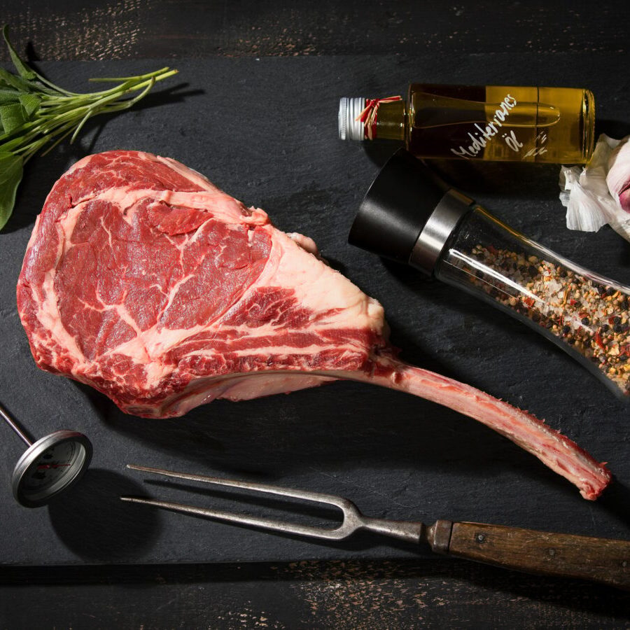 Raw tomahawk steak and ingredients